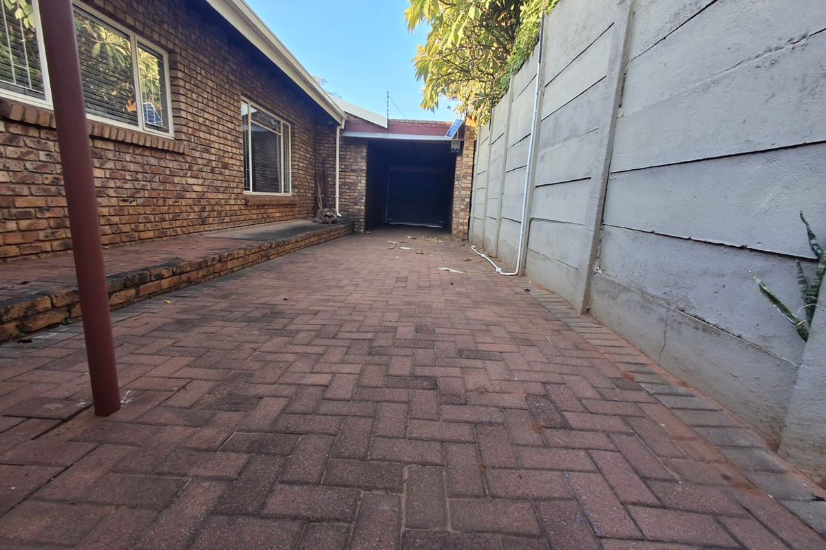 A paved side exterior area featuring face brick walls, a precast concrete boundary wall, and access to a garage.