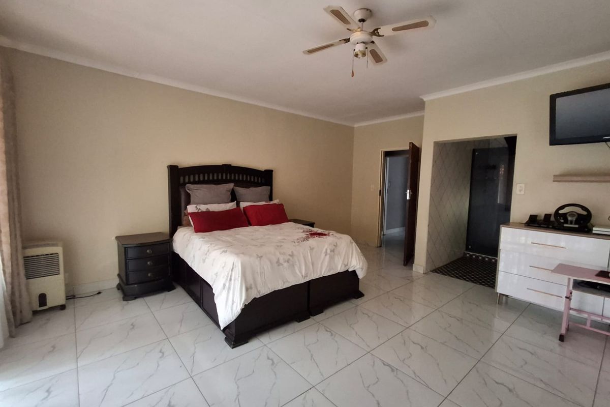 Spacious bedroom featuring modern marble-look floor tiles, a ceiling fan, and direct access to an en-suite bathroom.
