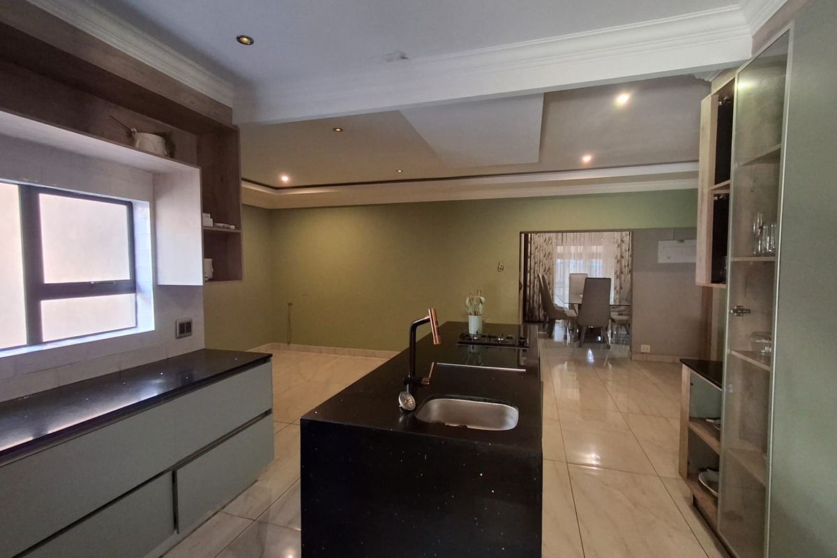 Modern kitchen featuring a central island with stone countertops, built-in cabinetry, and tiled flooring, offering an open-plan layout.
