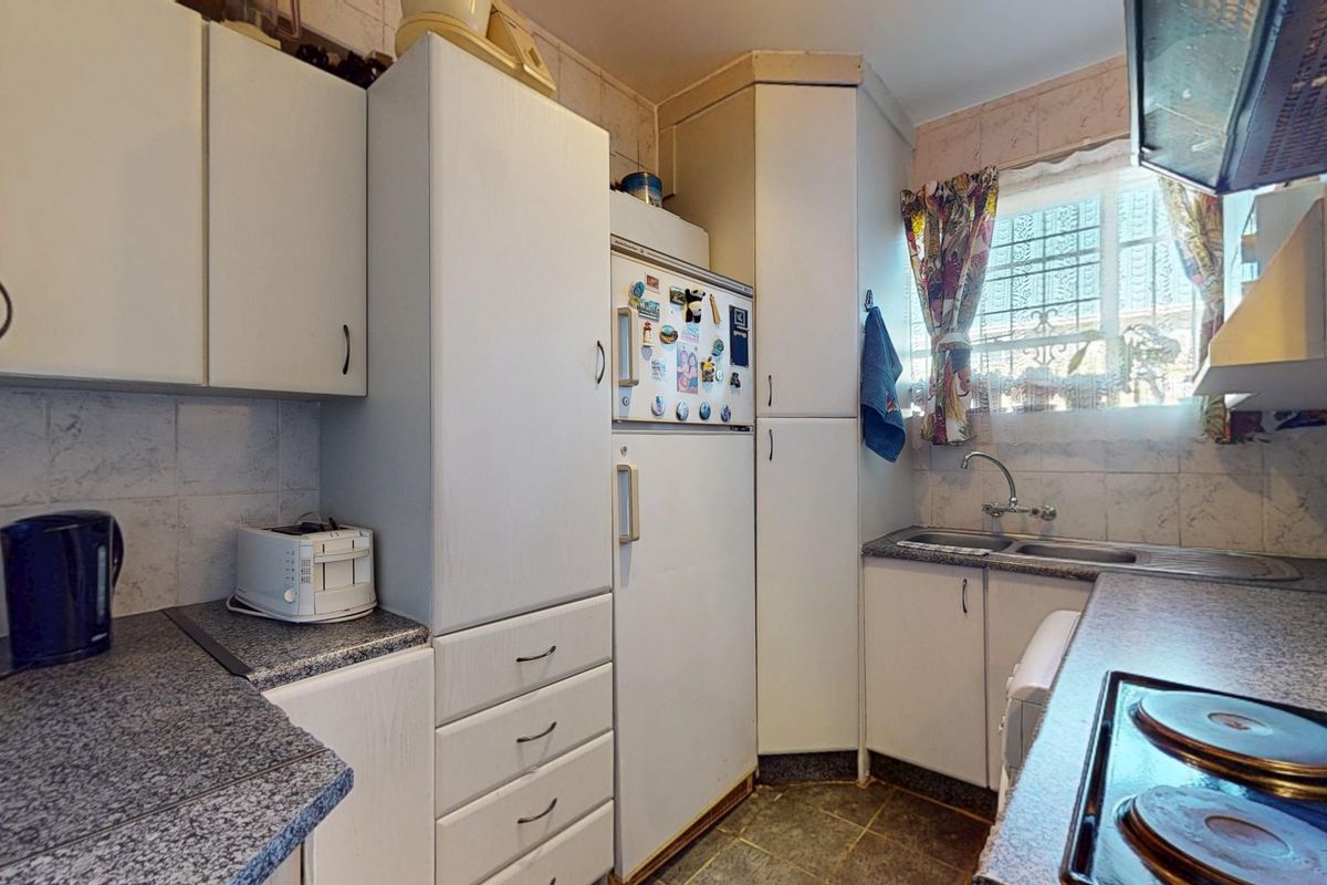 Compact kitchen featuring laminate cabinetry, granite-look countertops, a stainless steel double sink, and a built-in electric hob with an extractor fan.