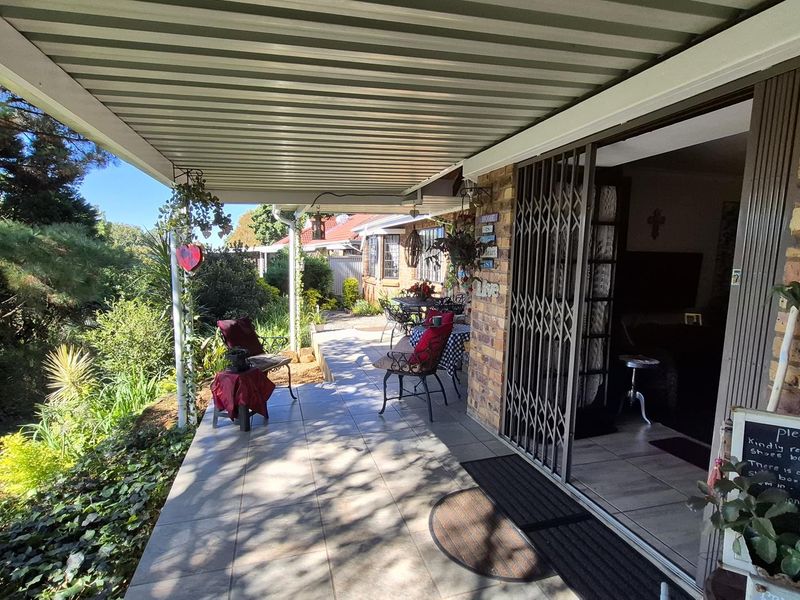 A covered patio area featuring tiled flooring, a corrugated metal roof, and direct access to the interior through a sliding glass door.