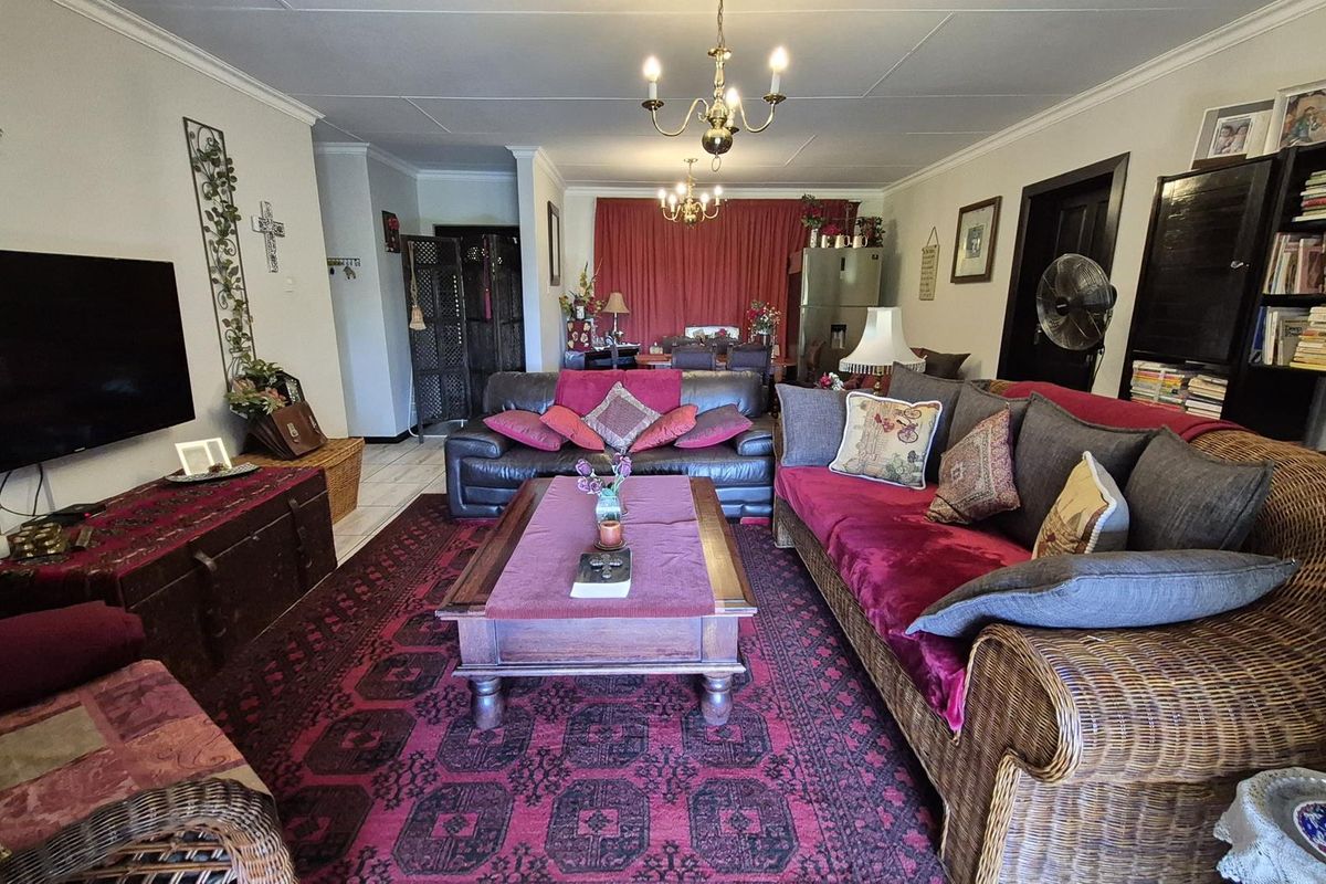 Spacious living room featuring tiled flooring, cove cornicing, and classic chandelier lighting, offering a comfortable and traditional living space.