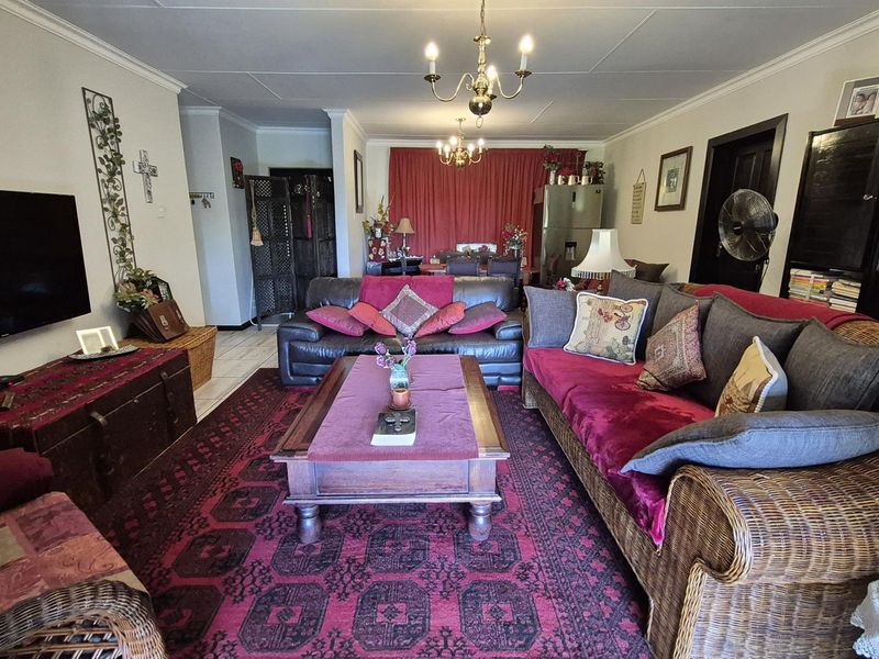 Spacious living room featuring tiled flooring, cove cornicing, and classic chandelier lighting, offering a comfortable and traditional living space.