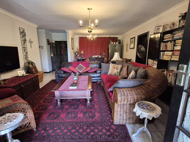 Spacious open-plan living and dining area featuring tiled flooring, classic ceiling cornices, and traditional chandelier lighting, offering a versatile layout for family living.