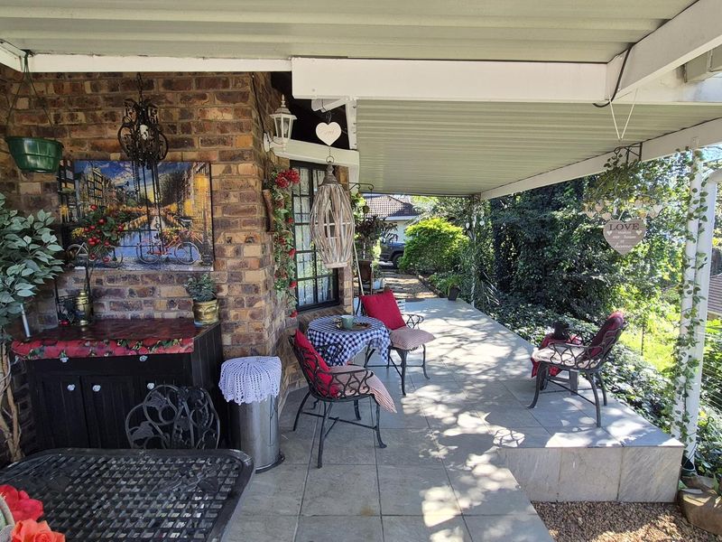 A covered outdoor patio featuring tiled flooring and exposed brick walls, providing a functional space for outdoor relaxation and entertainment.