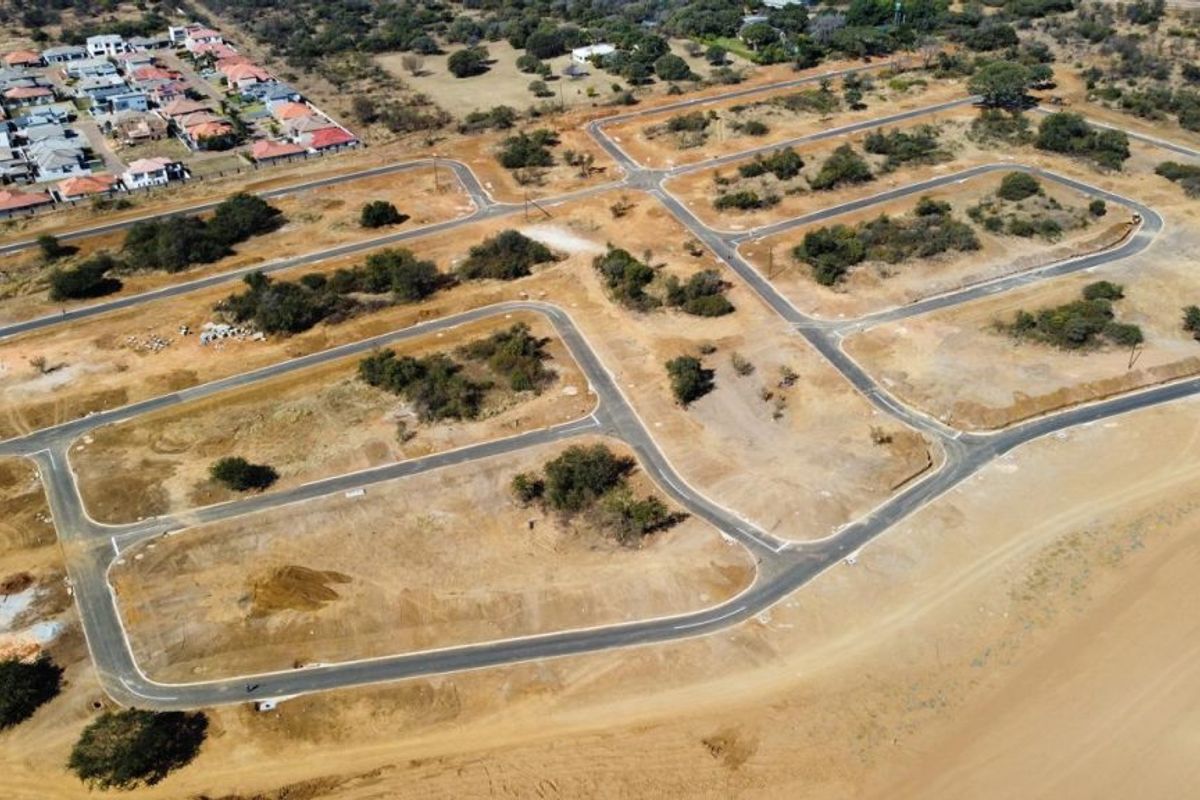 Aerial view of a residential development site featuring newly paved roads and subdivided plots ready for construction.