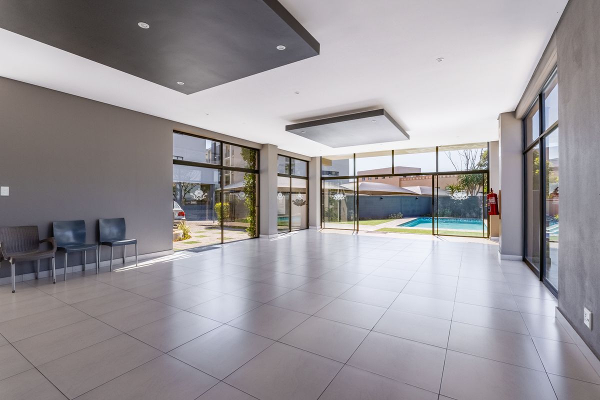 Spacious, open-plan living area featuring large floor-to-ceiling glass sliding doors, tiled flooring, and modern recessed ceiling bulkheads with views of the pool area.