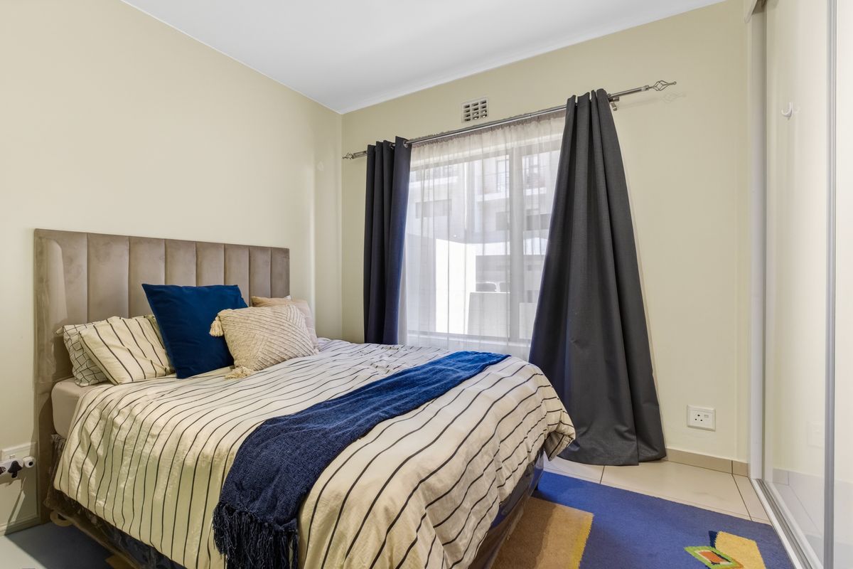 A well-maintained bedroom featuring tiled flooring, a built-in wardrobe with sliding mirror doors, and natural light through the window.
