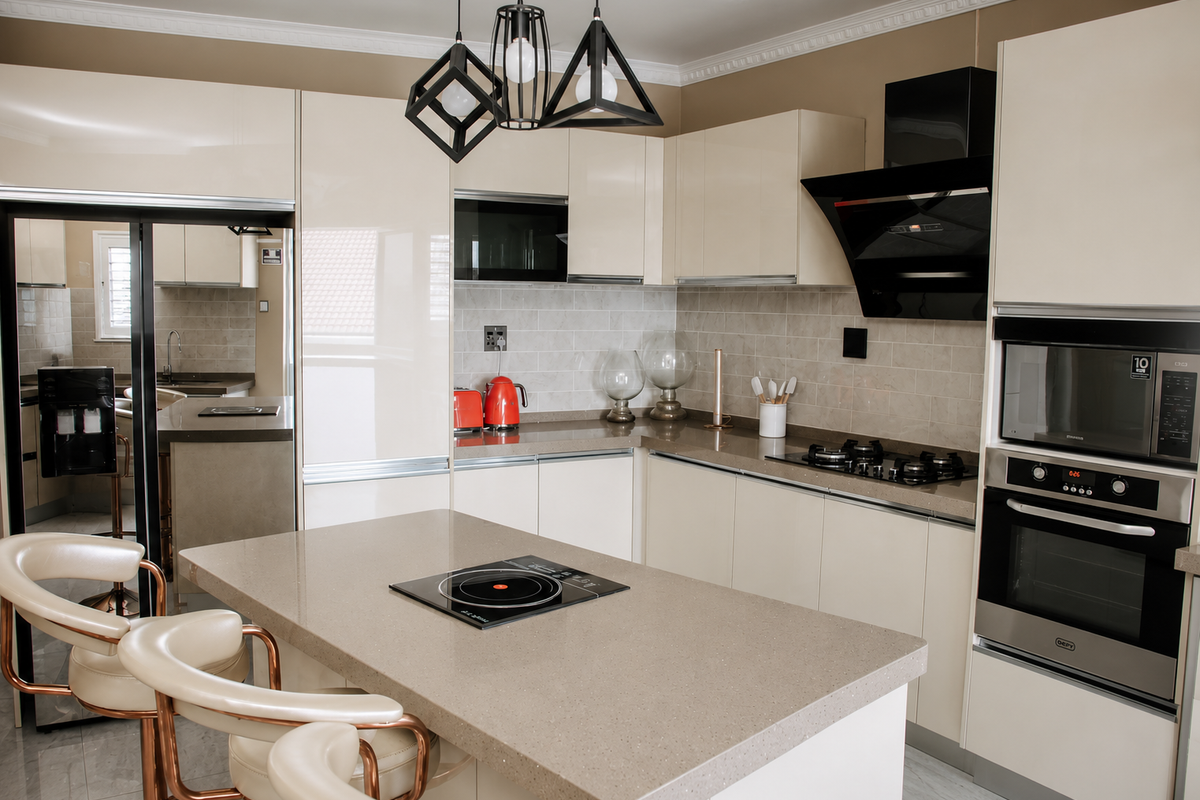 Modern kitchen featuring high-gloss cabinetry, stone countertops, a central island with a built-in hob, and integrated stainless steel appliances.