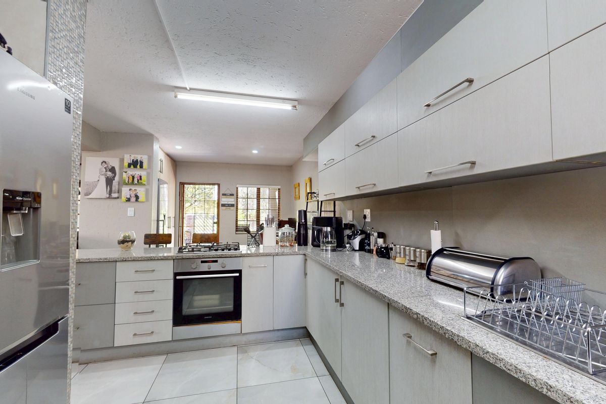 Modern kitchen featuring granite countertops, built-in oven, gas hob, and ample fitted cabinetry with a clean, functional layout.