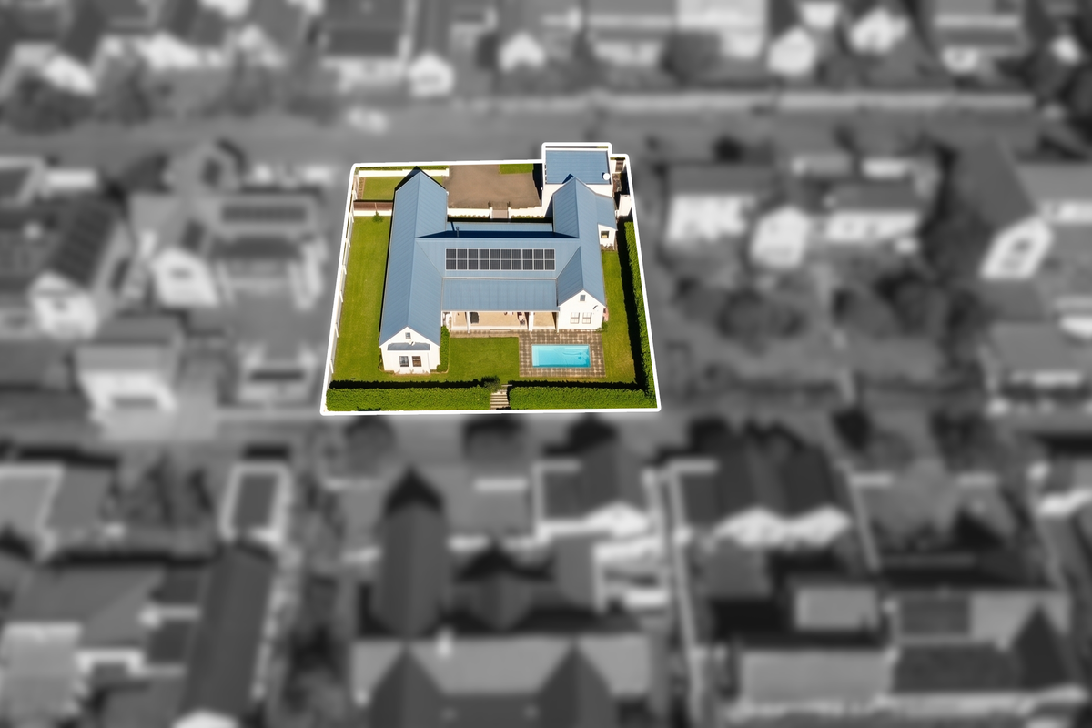 Aerial view of the property highlighting the house layout, blue metal roof, solar panels, swimming pool, and surrounding garden area.