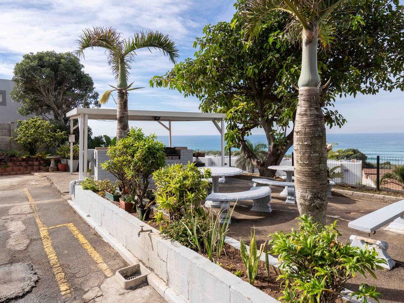 Outdoor entertainment area featuring a covered patio, built-in braai, and paved seating space with ocean views.