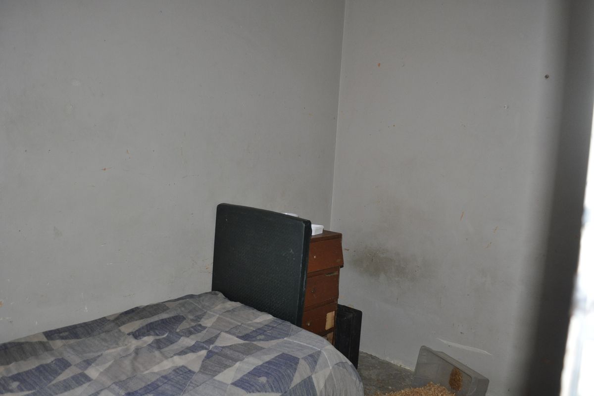 A bedroom interior featuring plain walls with visible surface staining and wear, requiring cosmetic attention and refurbishment.