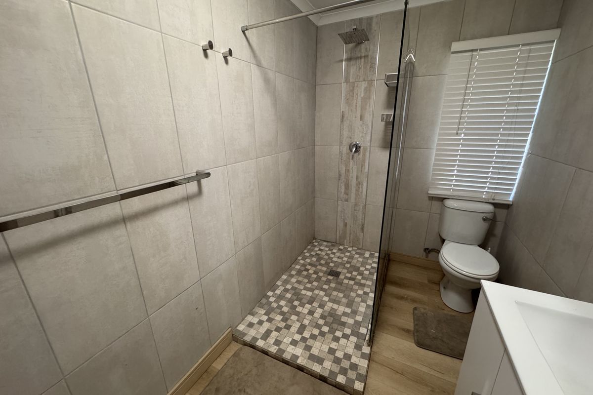 Modern bathroom featuring a walk-in shower with a rainfall showerhead, tiled walls, and a contemporary toilet.