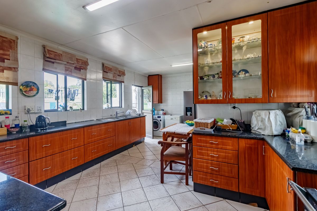 Spacious kitchen featuring extensive wooden cabinetry, granite countertops, tiled flooring, and ample natural light through multiple windows.
