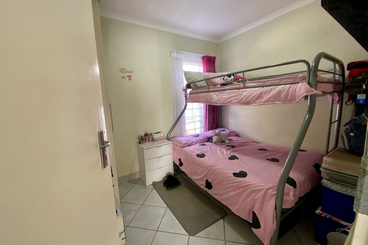 A compact bedroom featuring tiled flooring, a window with curtain tracks, and built-in cupboard space.