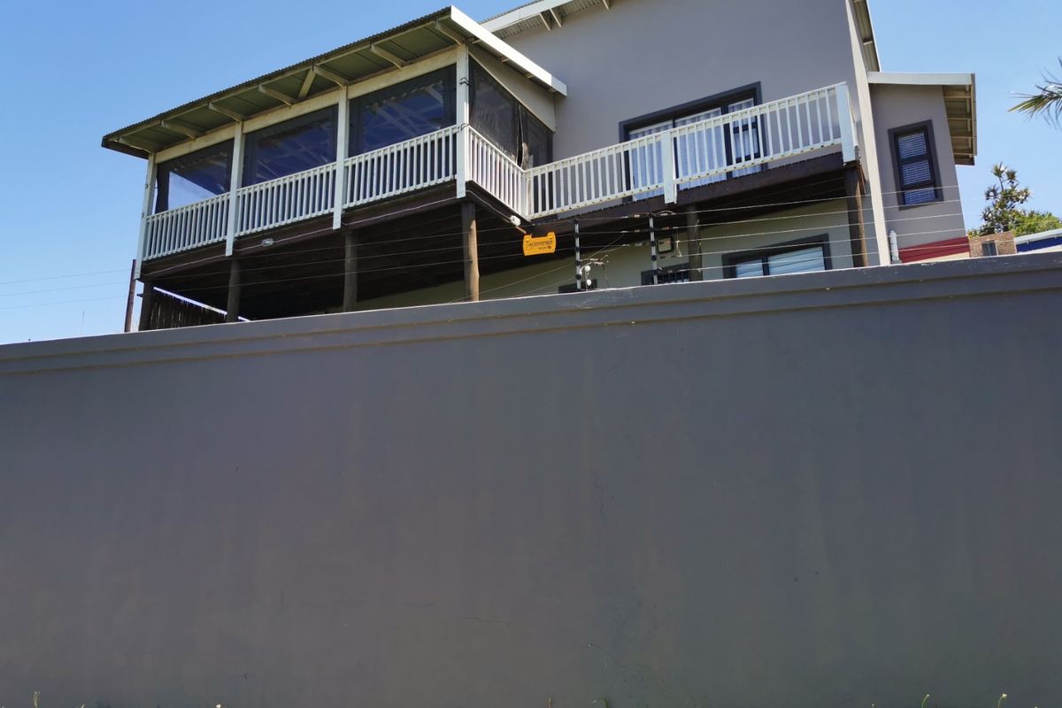 Rear view of the townhouse featuring a raised timber deck with a covered patio area, secured by perimeter walling and electric fencing.