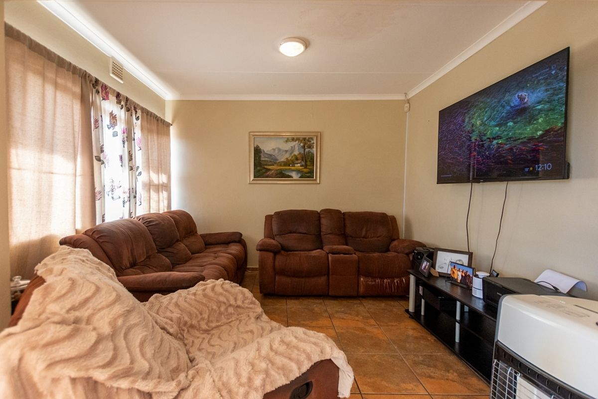 A comfortable living room featuring tiled flooring, coved ceiling cornices, and a wall-mounted television setup.
