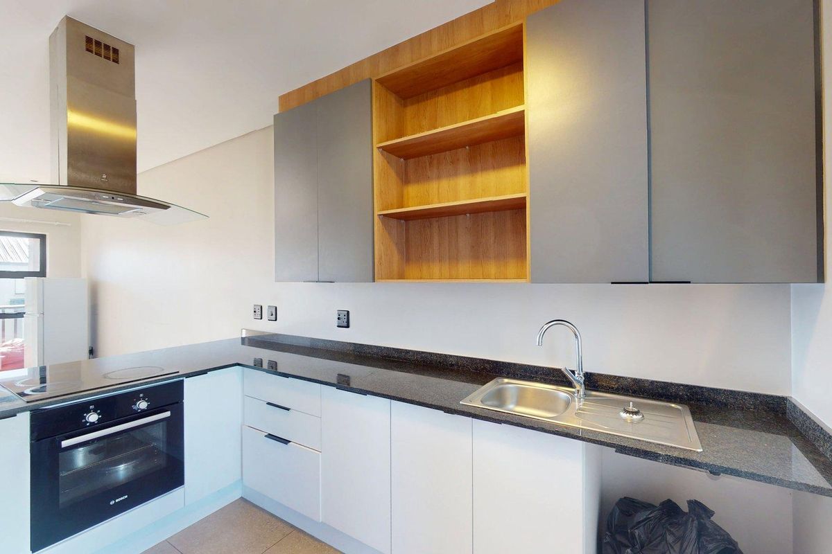 Modern kitchen featuring granite countertops, stainless steel sink, built-in oven, extractor fan, and a combination of white and wood-tone cabinetry.