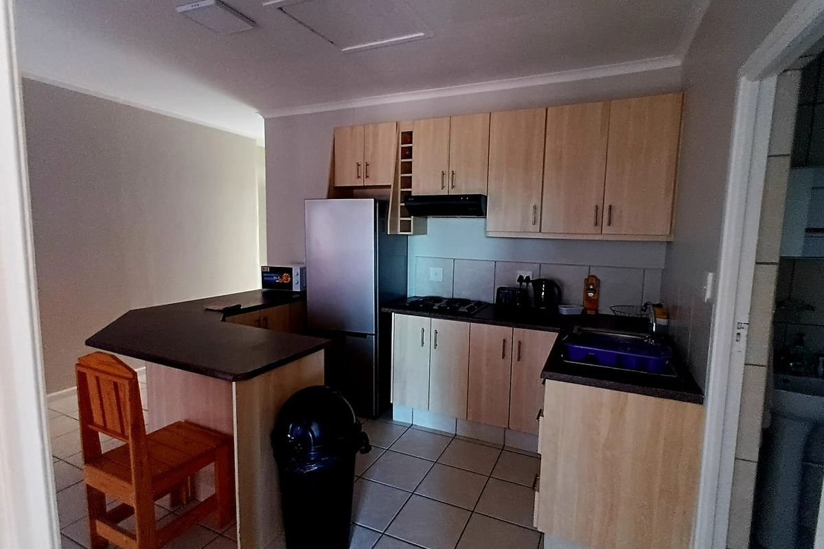 Functional kitchen featuring light wood cabinetry, dark laminate countertops, a breakfast nook, and tiled flooring, providing a practical layout for daily use.