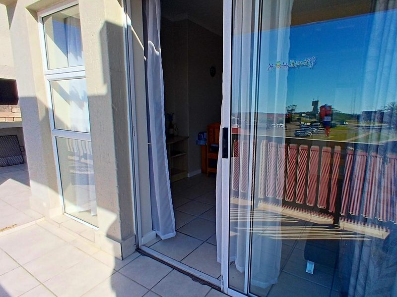 A tiled balcony featuring a built-in braai and sliding glass door access to the interior living space.