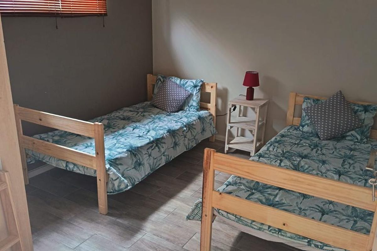 A bedroom featuring tiled flooring and venetian blinds, providing a functional space with neutral wall tones.
