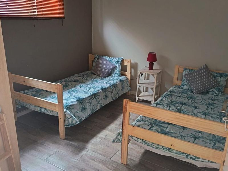 A bedroom featuring tiled flooring and venetian blinds, providing a functional space with neutral wall tones.