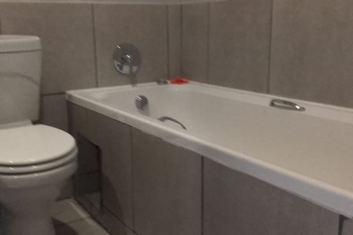 A functional bathroom featuring a standard toilet and a bathtub with tiled wall finishes.