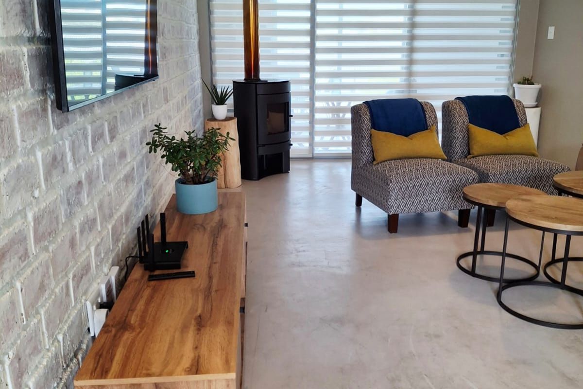 Modern living room featuring a striking exposed brick wall, polished concrete floors, and a contemporary freestanding wood-burning fireplace.
