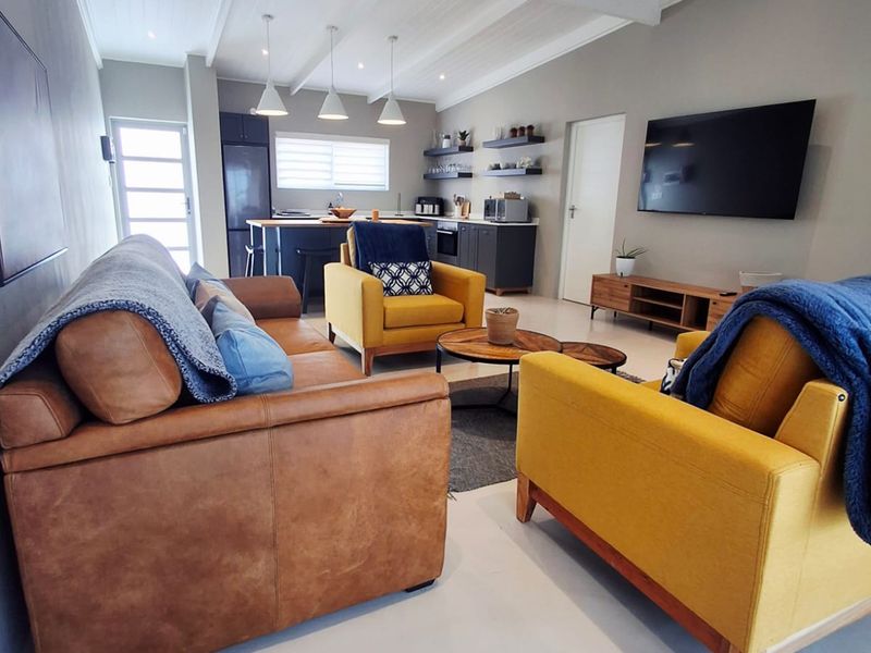 Spacious open-plan living area featuring a modern kitchen with island, exposed beam ceilings, and neutral finishes, creating a bright and functional living space.