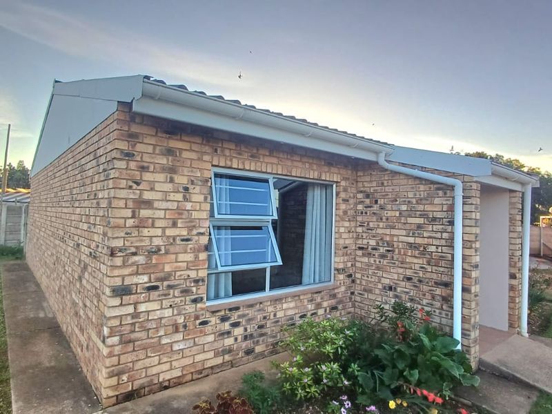 A view of the townhouse exterior featuring face brick construction, aluminium louvre windows, and functional guttering systems.