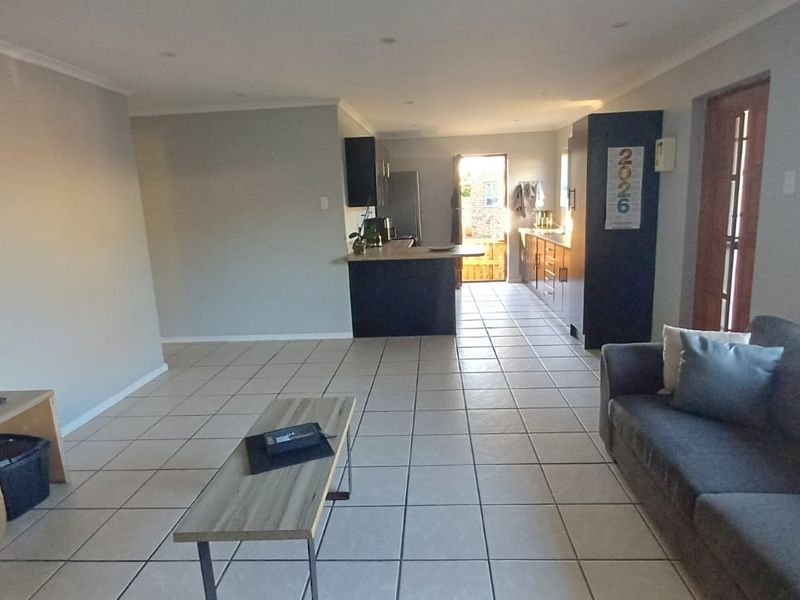 Open-plan living and kitchen area featuring tiled flooring, recessed lighting, and a functional kitchen layout with a central island.