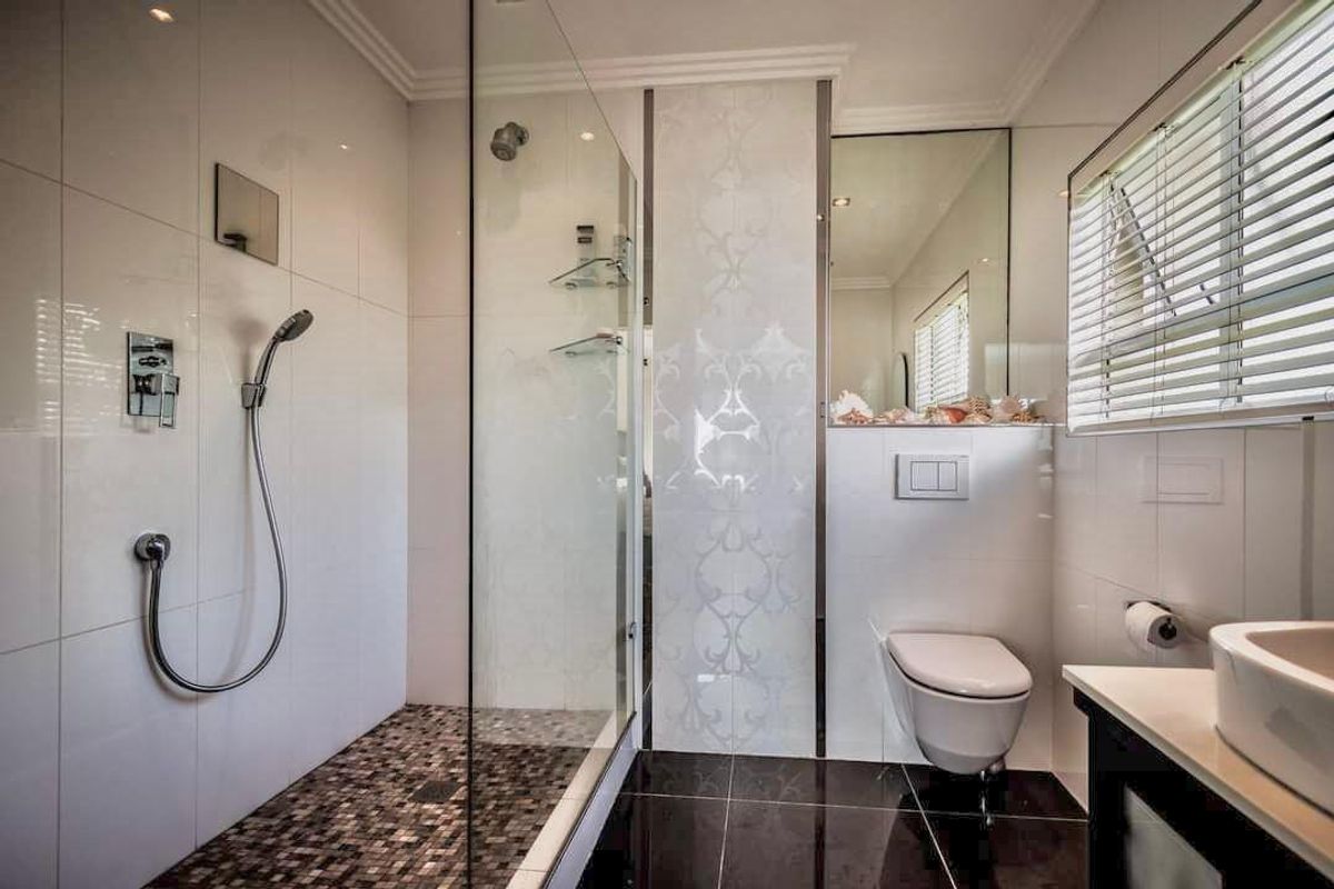 Modern bathroom featuring a spacious walk-in shower with glass screen, wall-mounted toilet, vessel sink vanity, and stylish mosaic floor tiling.