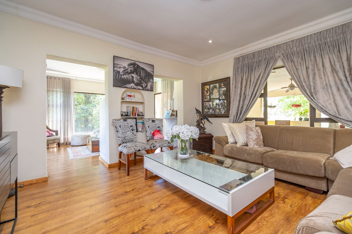 Spacious living room featuring warm laminate flooring, coved ceilings, and a built-in arched wall niche, with seamless flow to the adjacent living areas.