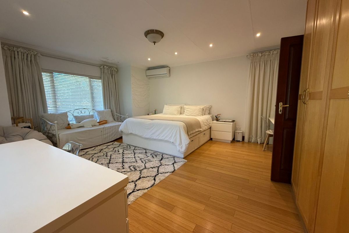 Spacious bedroom featuring laminate flooring, recessed lighting, a split-system air conditioner, and built-in wardrobe storage.