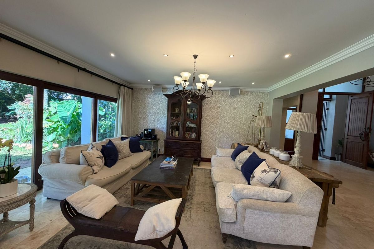 Spacious living room featuring stone flooring, crown molding, and large sliding glass doors that provide ample natural light and garden views.