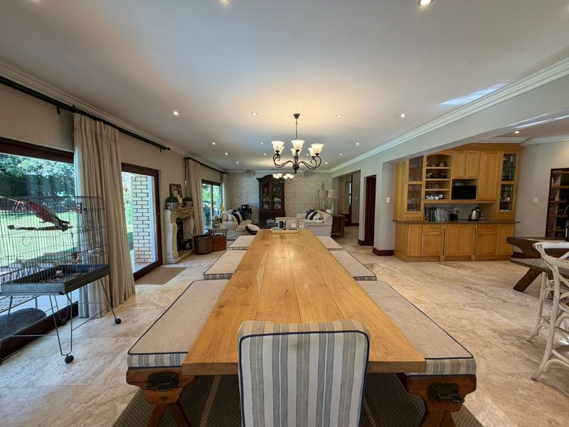 Spacious open-plan living and dining area featuring stone flooring, a stone fireplace, and custom built-in cabinetry with direct access to the garden.