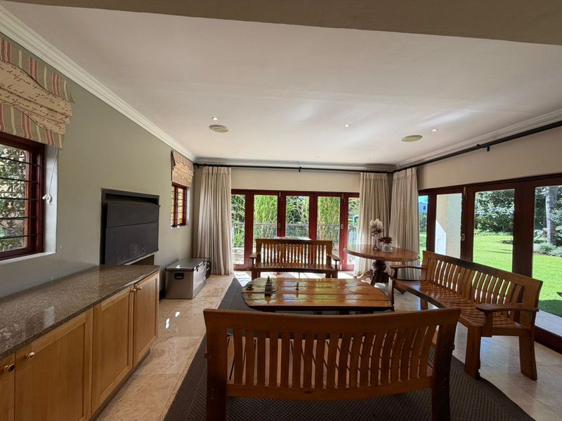 Spacious living area featuring tiled flooring, built-in cabinetry with granite countertops, and large timber-framed glass doors providing access to the garden.