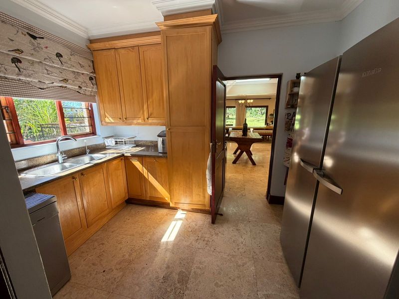 A functional kitchen featuring warm wooden cabinetry, granite countertops, and stone tile flooring, with a view through to the adjacent dining area.