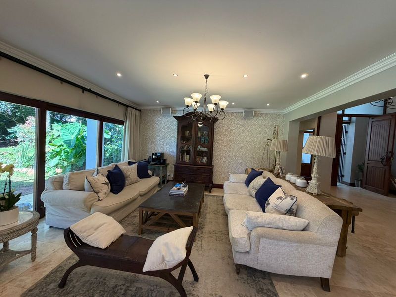 Spacious living room featuring stone flooring, crown molding, and large sliding glass doors that provide ample natural light and garden views.