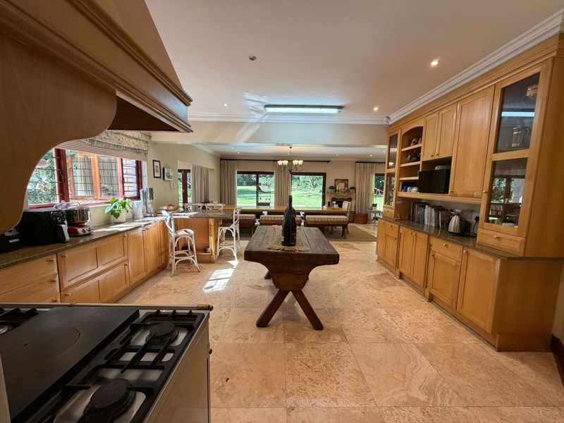 Spacious open-plan kitchen and living area featuring natural stone flooring, extensive timber cabinetry, and direct access to the rear garden through sliding doors.