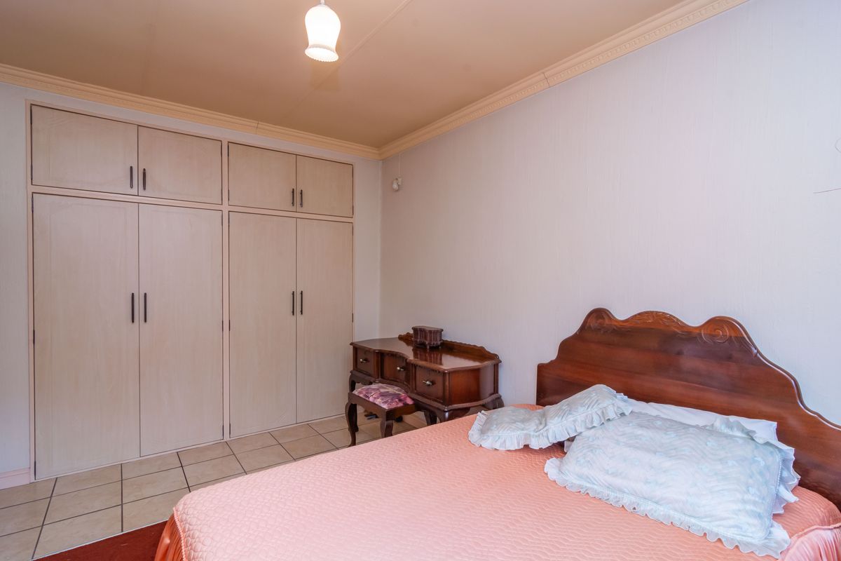 A bedroom featuring built-in cupboards, tiled flooring, and decorative ceiling cornice.