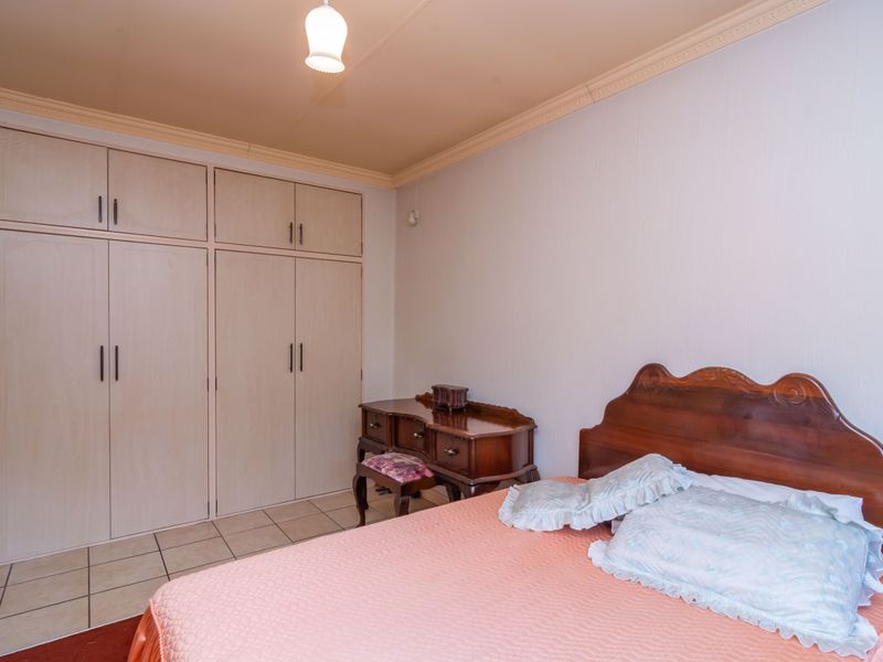 A bedroom featuring built-in cupboards, tiled flooring, and decorative ceiling cornice.