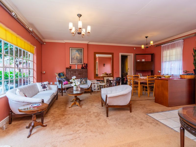Open-plan living and dining area featuring a brick fireplace, coved ceilings, and a mix of carpeted and tiled flooring.