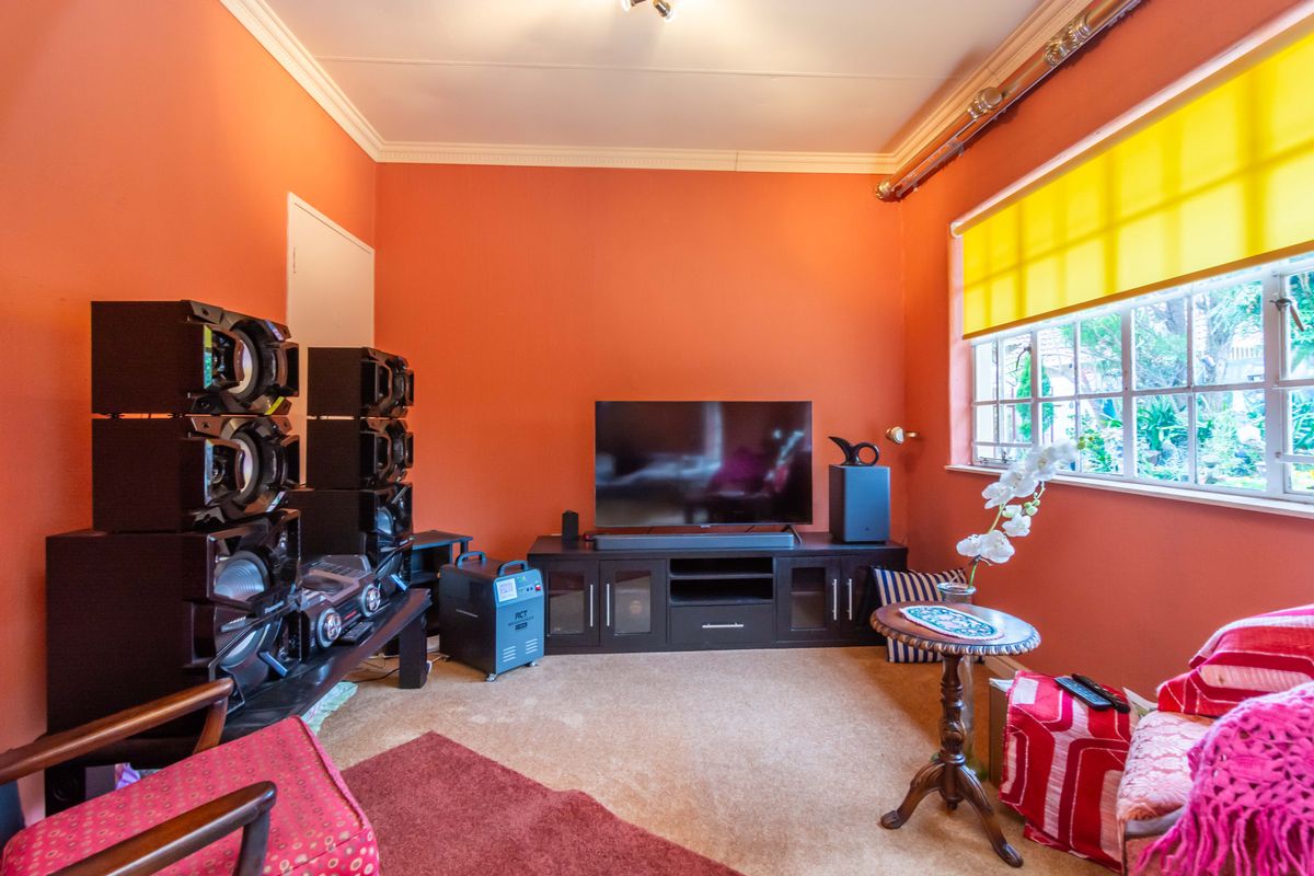 A living room featuring orange walls, crown molding, and a window with a yellow roller blind.