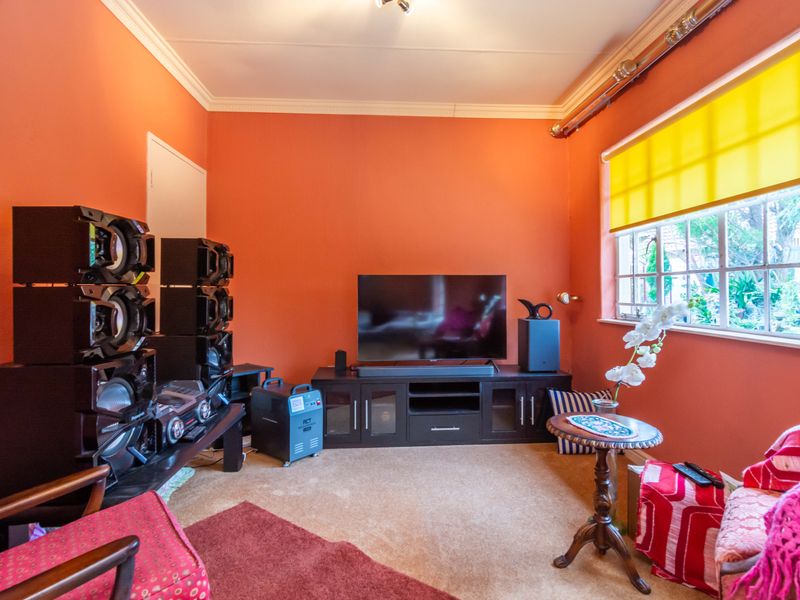 A living room featuring orange walls, crown molding, and a window with a yellow roller blind.