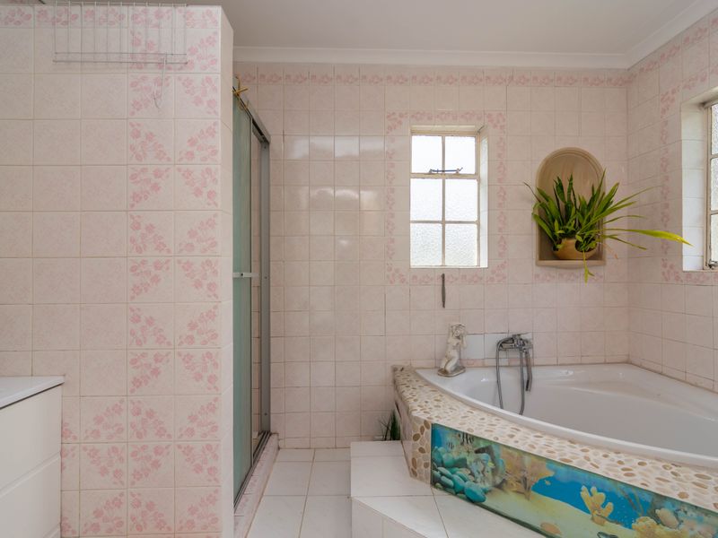 Bathroom featuring a corner bathtub with decorative tiling, a separate shower enclosure, and classic wall tiles with a floral border.