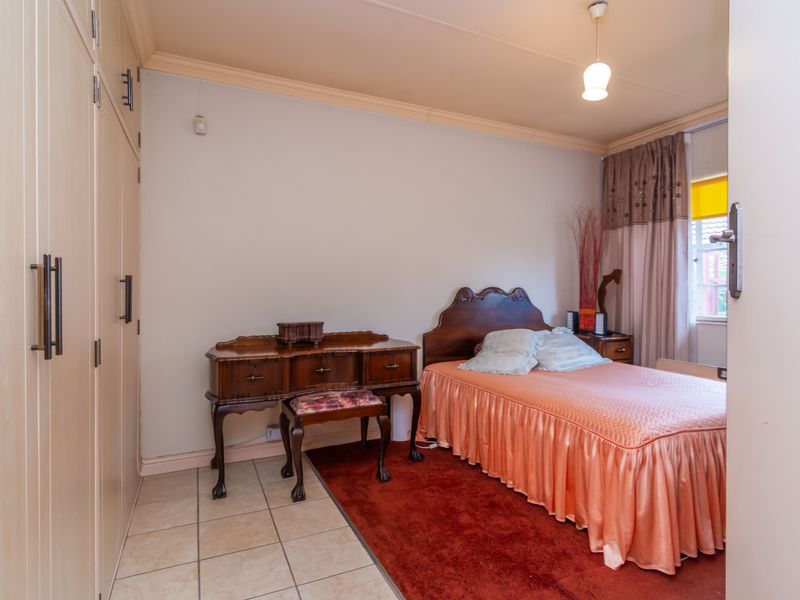 A bedroom featuring built-in cupboards, tiled flooring, and decorative cornice detailing.