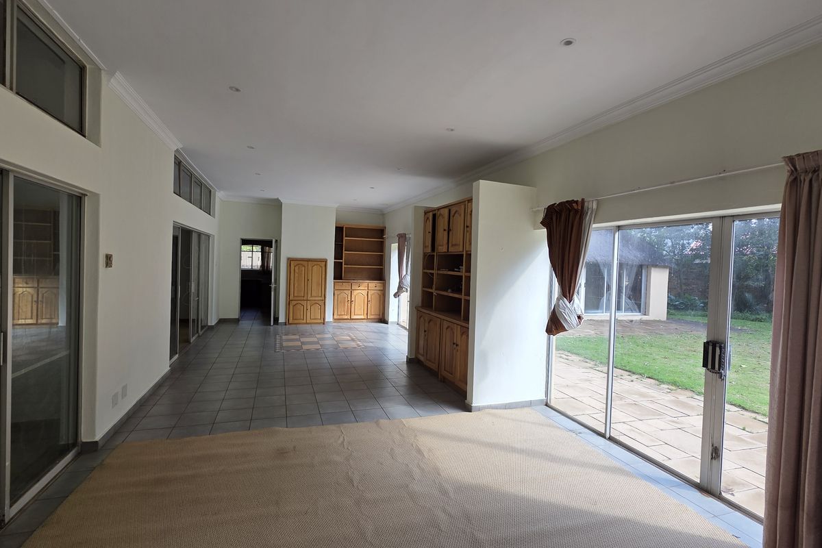 Spacious, light-filled living area featuring tiled flooring, built-in cabinetry, and large sliding glass doors providing direct access to the rear garden.