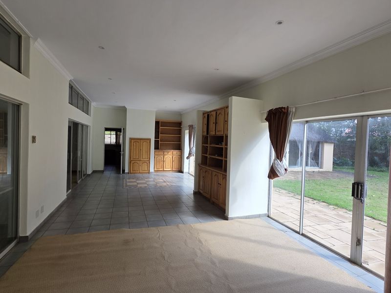 Spacious, light-filled living area featuring tiled flooring, built-in cabinetry, and large sliding glass doors providing direct access to the rear garden.